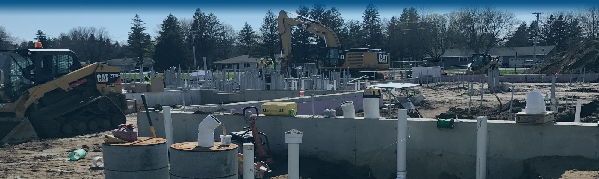 Residential housing development in the early stages of construction showing basement foundations with city septic and water line hookups